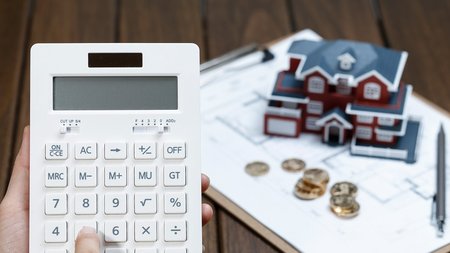 female-hand-operating-calculator-front-villa-house-model